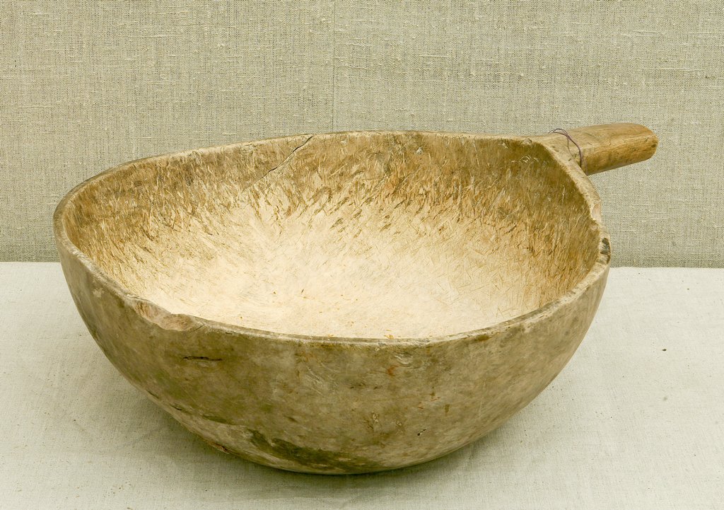 Деревянный выдолбленный ковш с ручкой. Поверхность гладкая, светло-коричневого цвета, без украшений